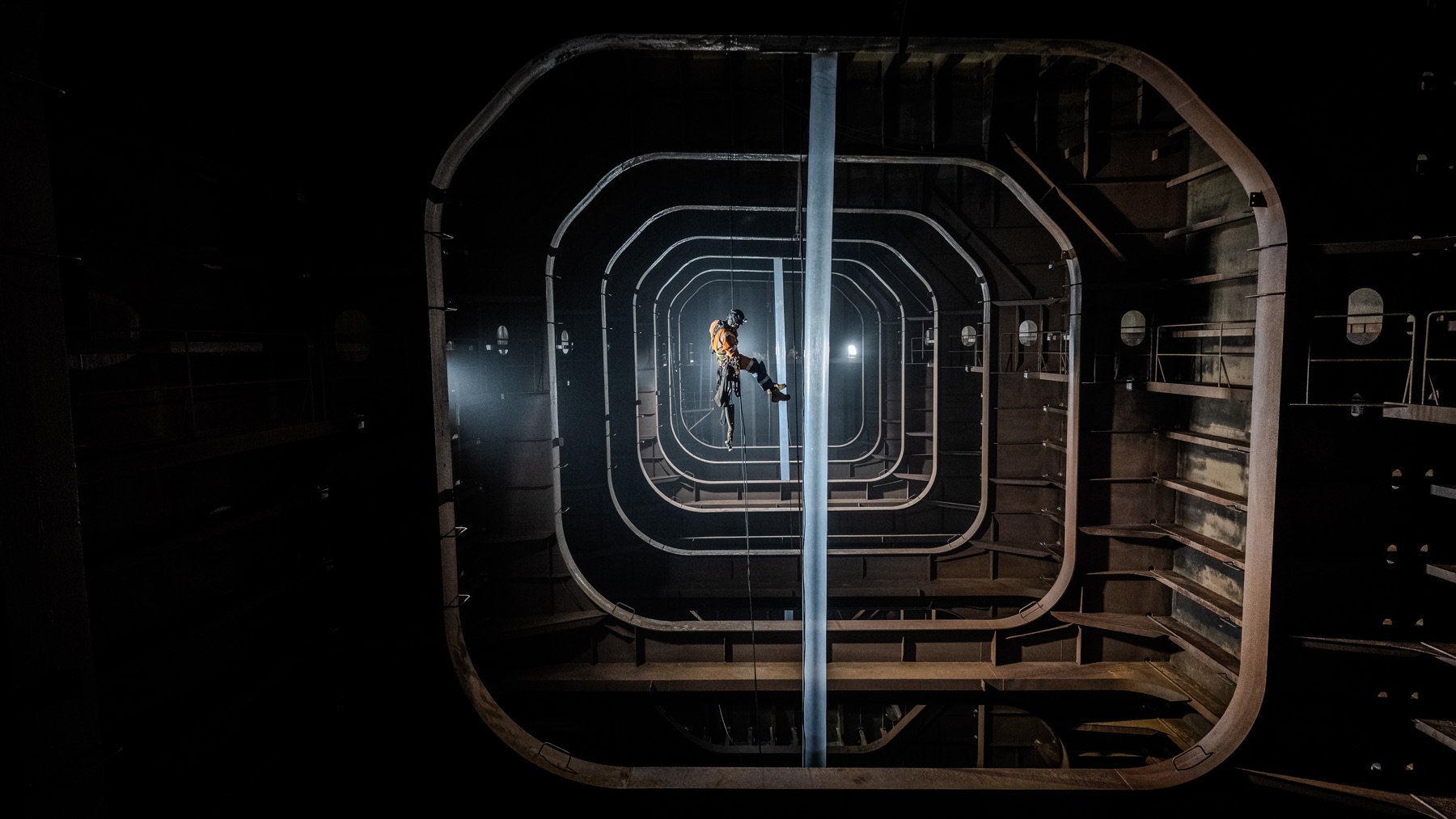 Rope-access technician descending the centre of a ship's tank